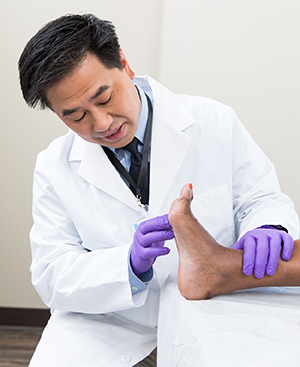 Healthcare provider examining man’s foot.