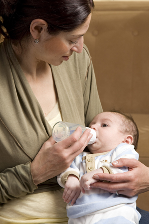 Una madre alimenta al recién nacido con un biberón.
