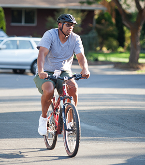 Hombre que anda en bicicleta por una calle de su vecindario.