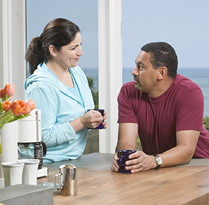 Un hombre y una mujer hablando en la cocina mientras toman un café.