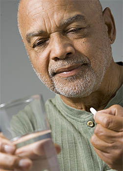 Hombre a punto de tomar una píldora con un vaso de agua.