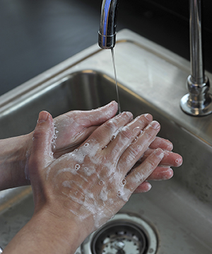 Primer plano de manos que se lavan con agua y jabón en el lavabo.