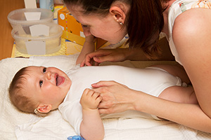 Un niño con un audífono en el oído se ríe e interactúa con su madre.