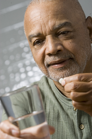 Man holding glass of water, preparing to take pill.