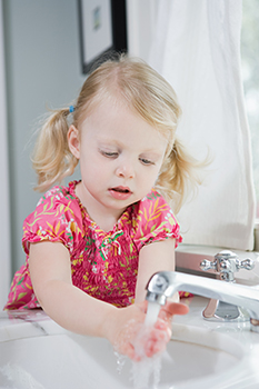 Girl washing her hands in a bathroom sink