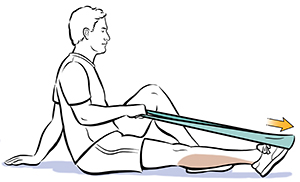 Man sitting on floor holding ends of elastic band wrapped around foot, pointing toes away from him.