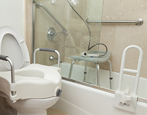 Bathroom set up with grab bars, commode seat, and other safety features.