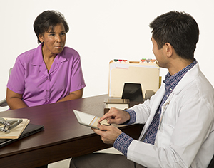 Woman sitting at desk talking to doctor.