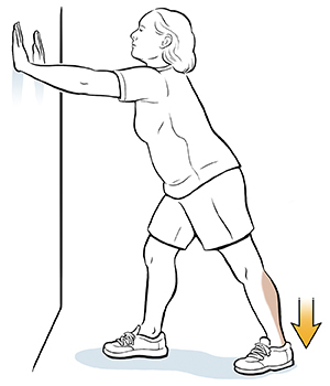 Woman leaning hands on wall doing calf stretch.