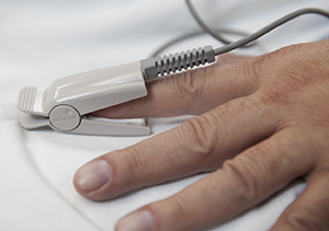 Closeup of pulse oximeter on man's finger.