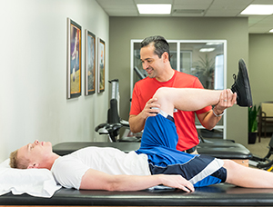 Physical therapist working with man's knee.