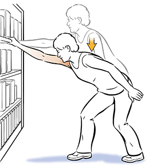 Mujer que hace un ejercicio de elevación del hombro, sosteniéndose de una biblioteca. 