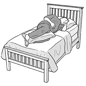 Hombre acostado de lado en la cama con una almohada entre las rodillas.