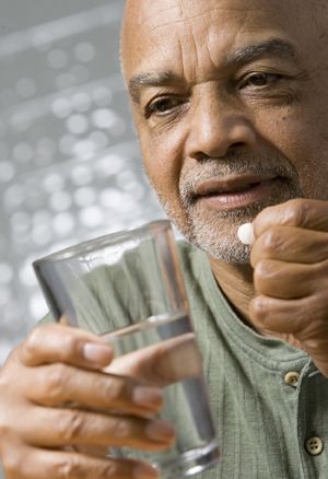 Hombre que sostiene un vaso de agua, preparándose para tomar una pastilla.