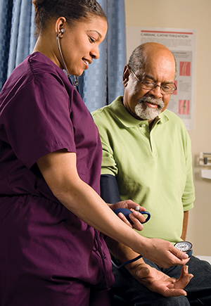 Una enfermera mide la presión arterial de un paciente varón mayor.