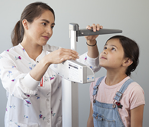 Un proveedor de atención médica midiendo la altura de una niña.