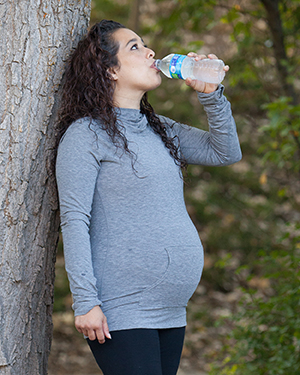 Una embarazada bebe agua embotellada.