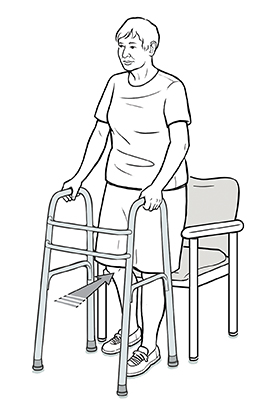 Mujer con un andador retrocediendo hacia una silla, con una mano en el andador y la otra en el apoyabrazos de la silla. La silla está en contacto con la parte posterior de sus piernas.