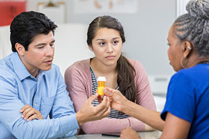 Padre e hija hablando de medicamentos con un farmacéutico.