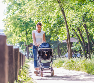 Mujer caminando al aire libre con el bebé en un cochecito.