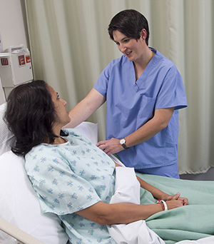 Mujer en una cama de hospital hablando con un proveedor de atención médica.