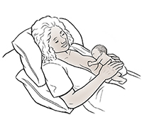 Mujer recostada amamantando un bebé prematuro.