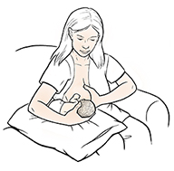 Mujer amamantando un bebé prematuro en posición de “fútbol”.