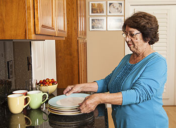 Mujer junto a la encimera de la cocina, levantando un plato limpio.