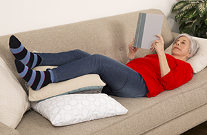 Mujer acostada en un sofá con los pies levantados.