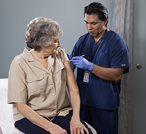 Un proveedor de atención médica pone una inyección en la parte superior del brazo de una mujer.
